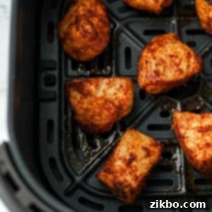 An air fryer basket with several unbreaded chicken bites.
