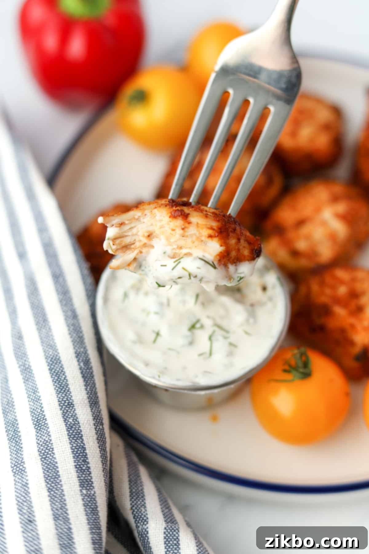 A fork dipping a small piece of chicken into ranch dressing.