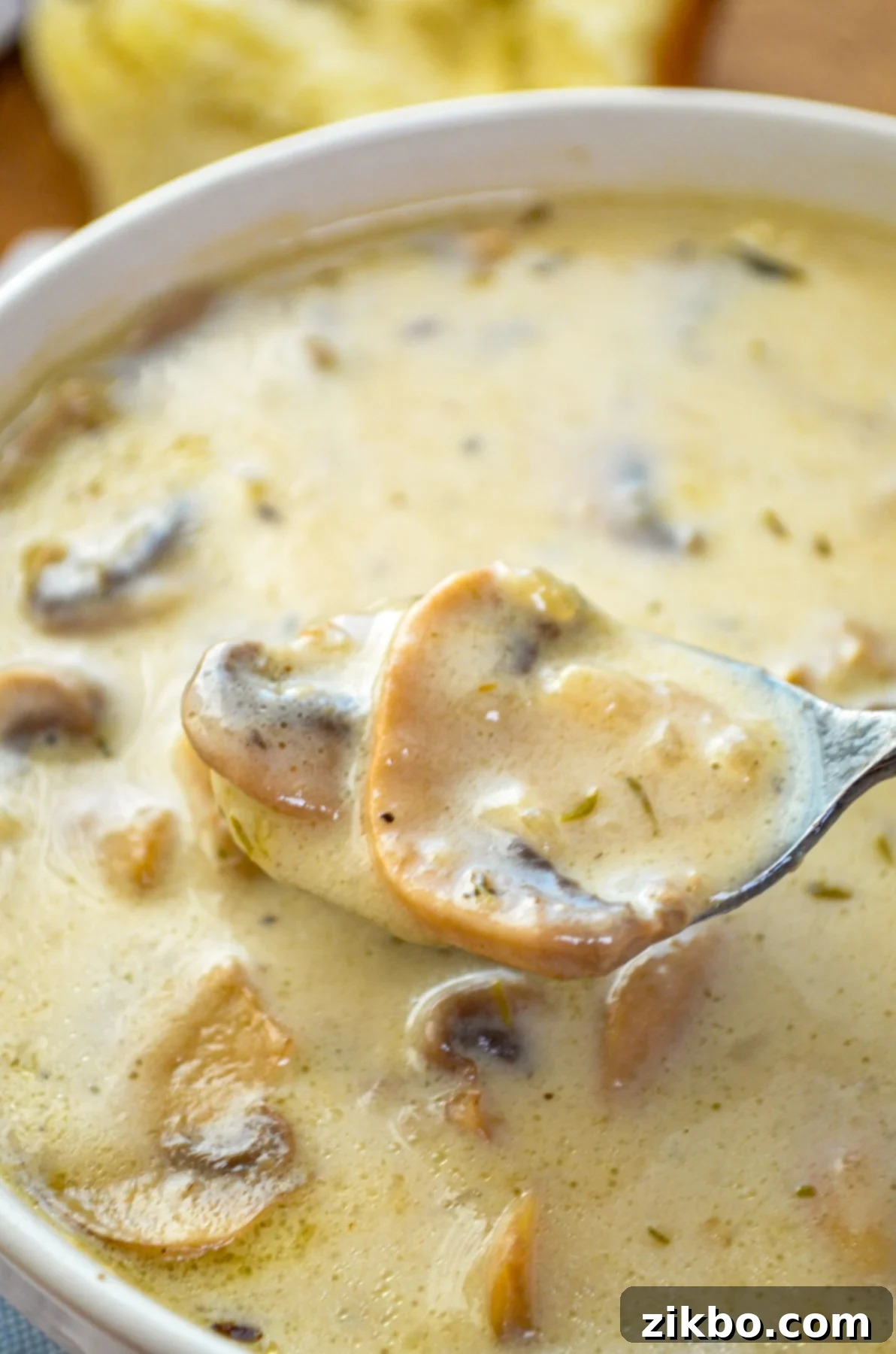 A bowl of mushroom soup with a spoon taking a spoonful.
