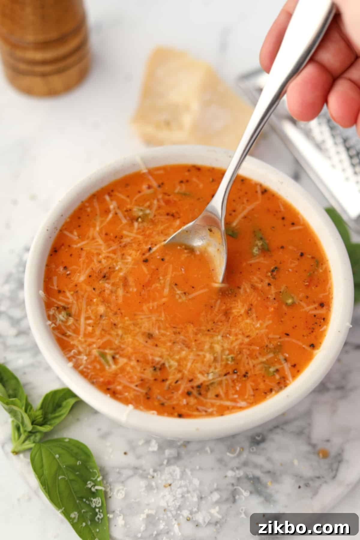 A spoon stirring a bowl of tomato soup.