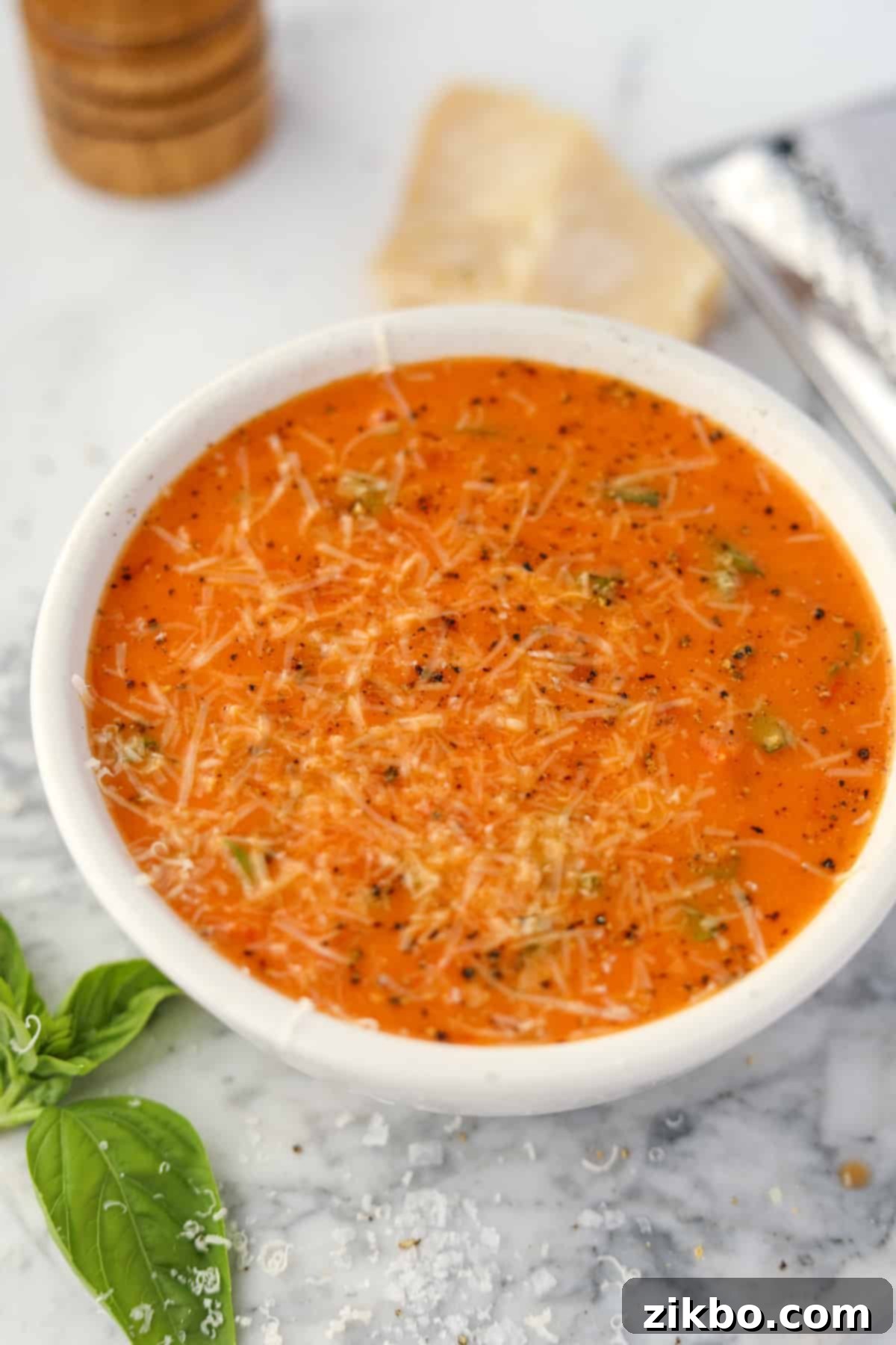 A white bowl filled with creamy tomato soup.