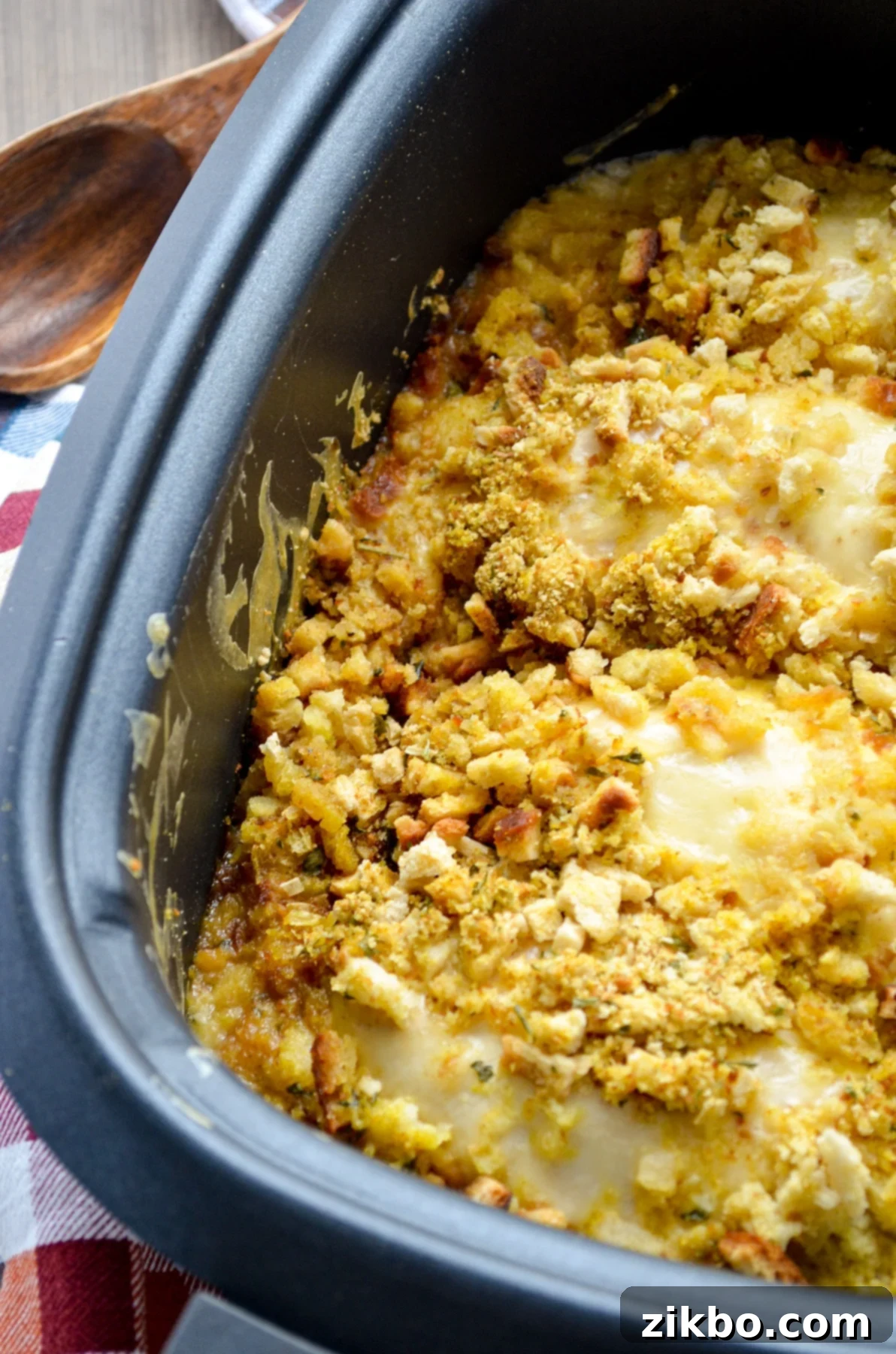A slow cooker filled with stuffing and swiss cheese covered chicken breasts.