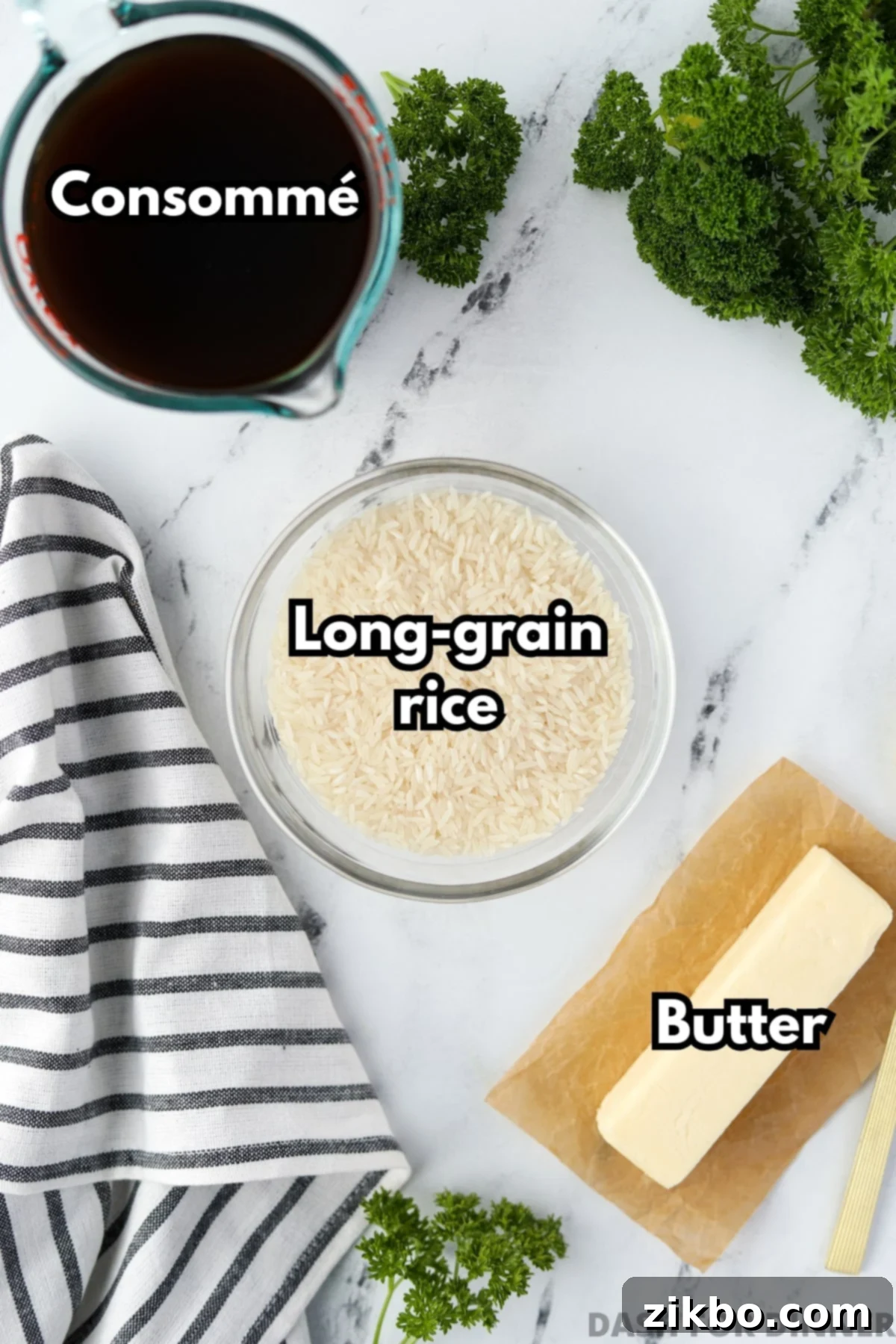 A bowl of rice, a measuring cup of consomme, and a stick of butter.