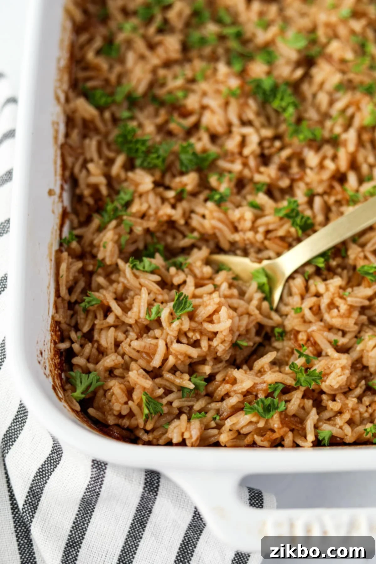 Scooping a pile of fluffy rice from a baking dish.