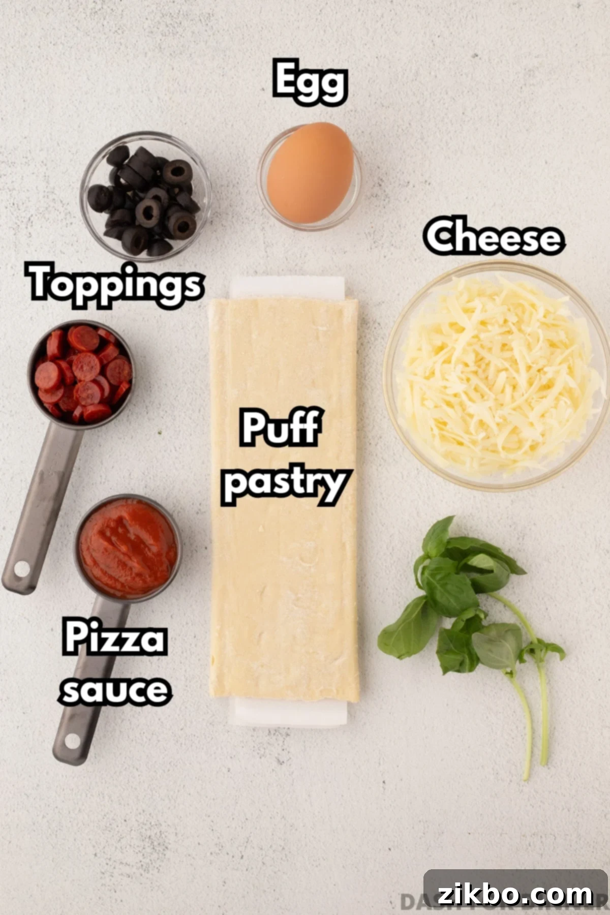 Golden Flaky Pizza Perfection 3 The essential ingredients laid out for making puff pastry pizza: sauce, puff pastry, cheese, various toppings, and an egg for egg wash.