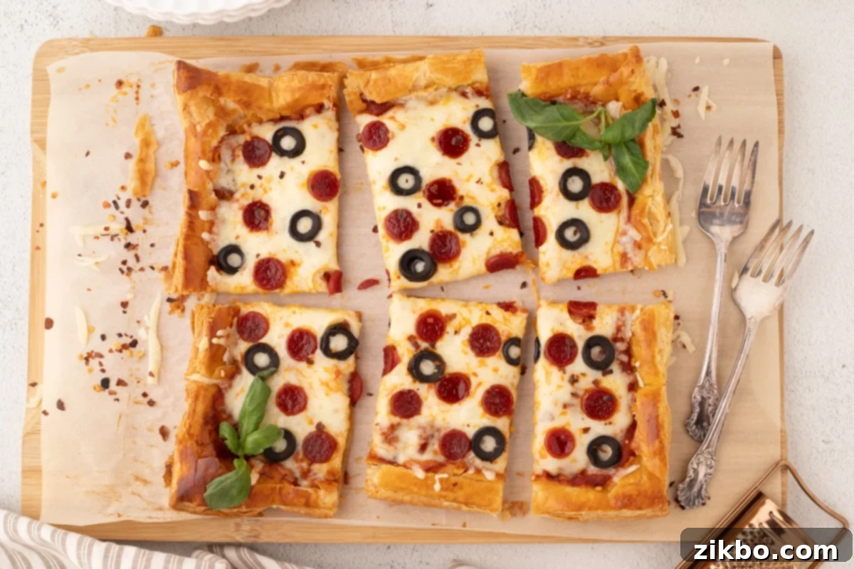 Golden Flaky Pizza Perfection 7 Slices of puff pastry pizza on a wooden cutting board, featuring pepperoni, olives, and a garnish of vibrant fresh basil.