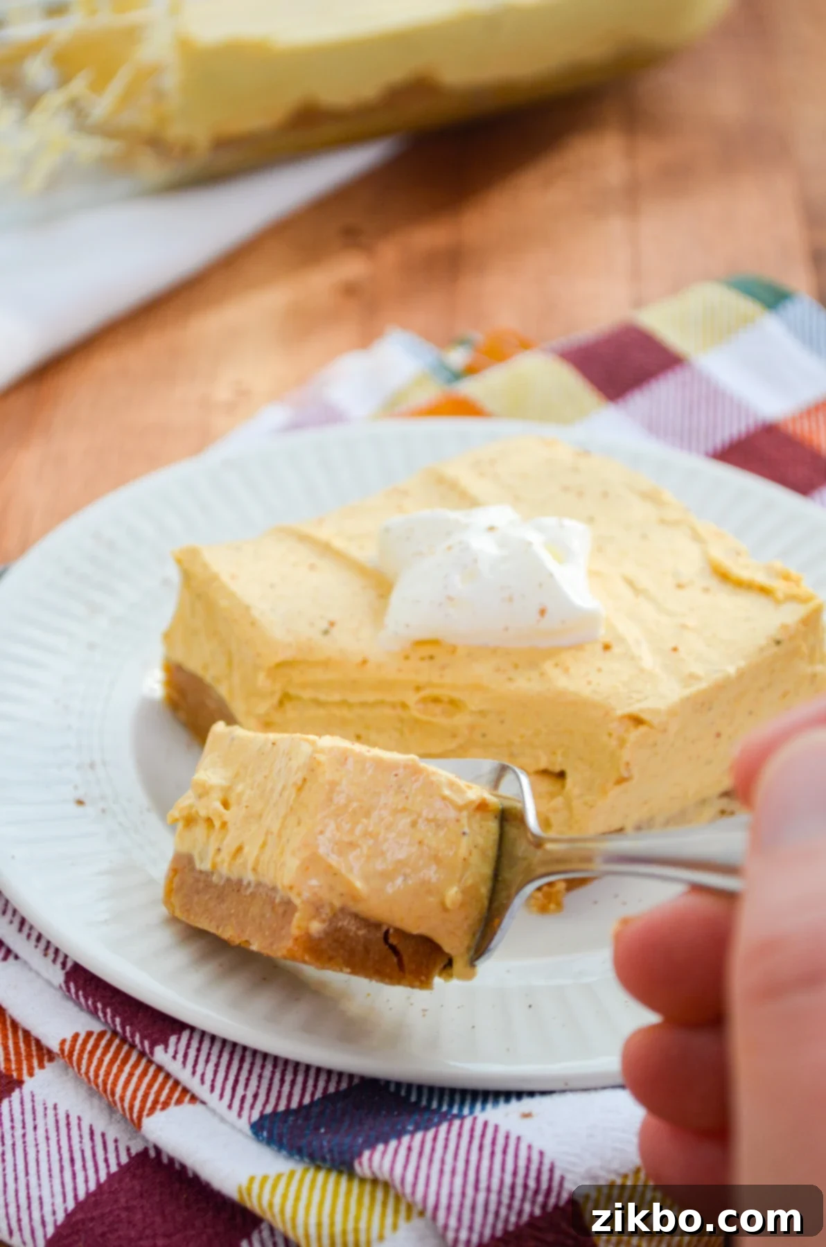 A slice of pumpkin cheesecake bars, showcasing the creamy filling and graham cracker crust.