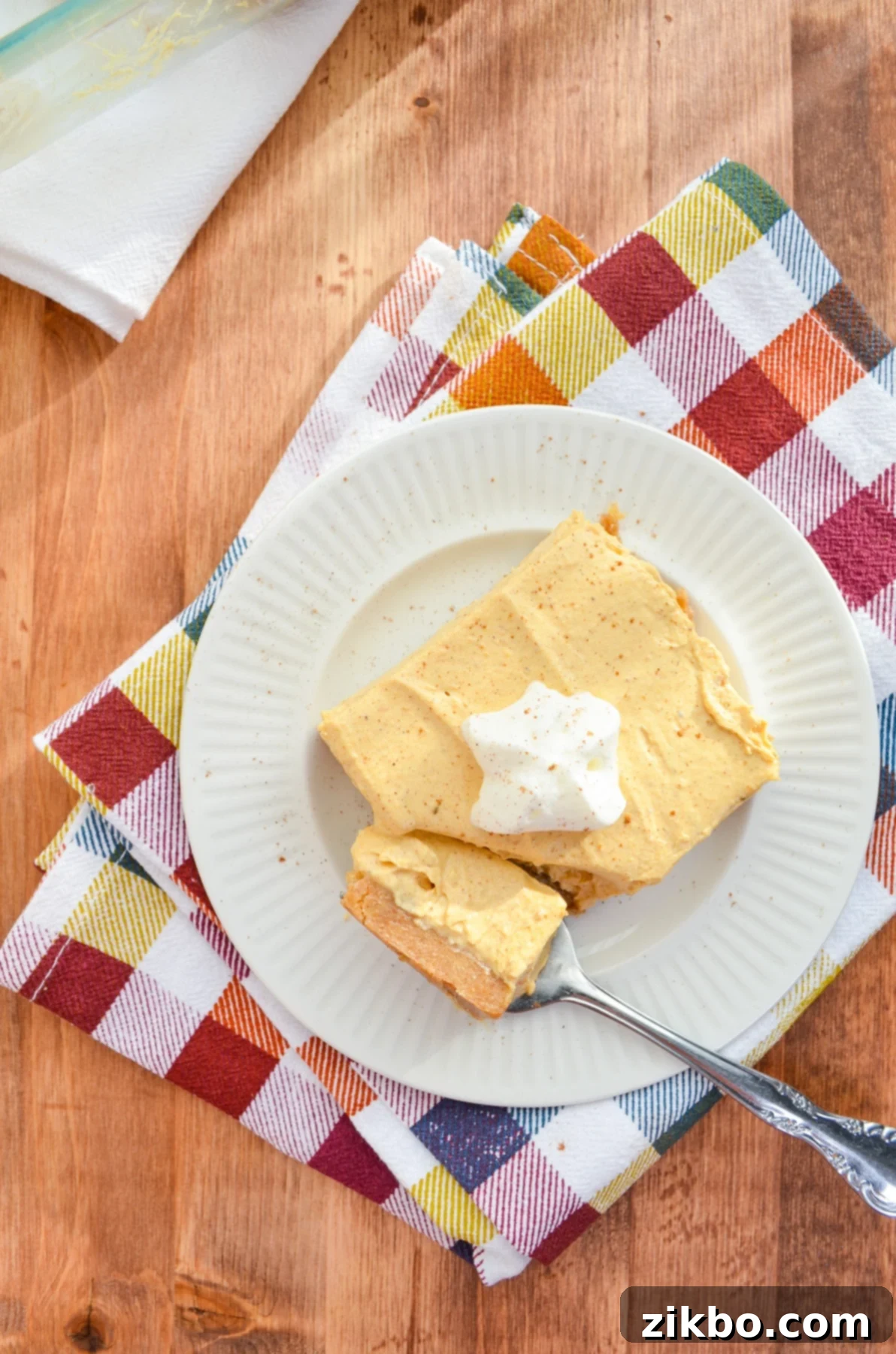 A slice of no bake pumpkin cheesecake bars, elegantly presented on a colorful napkin, ready to be enjoyed.