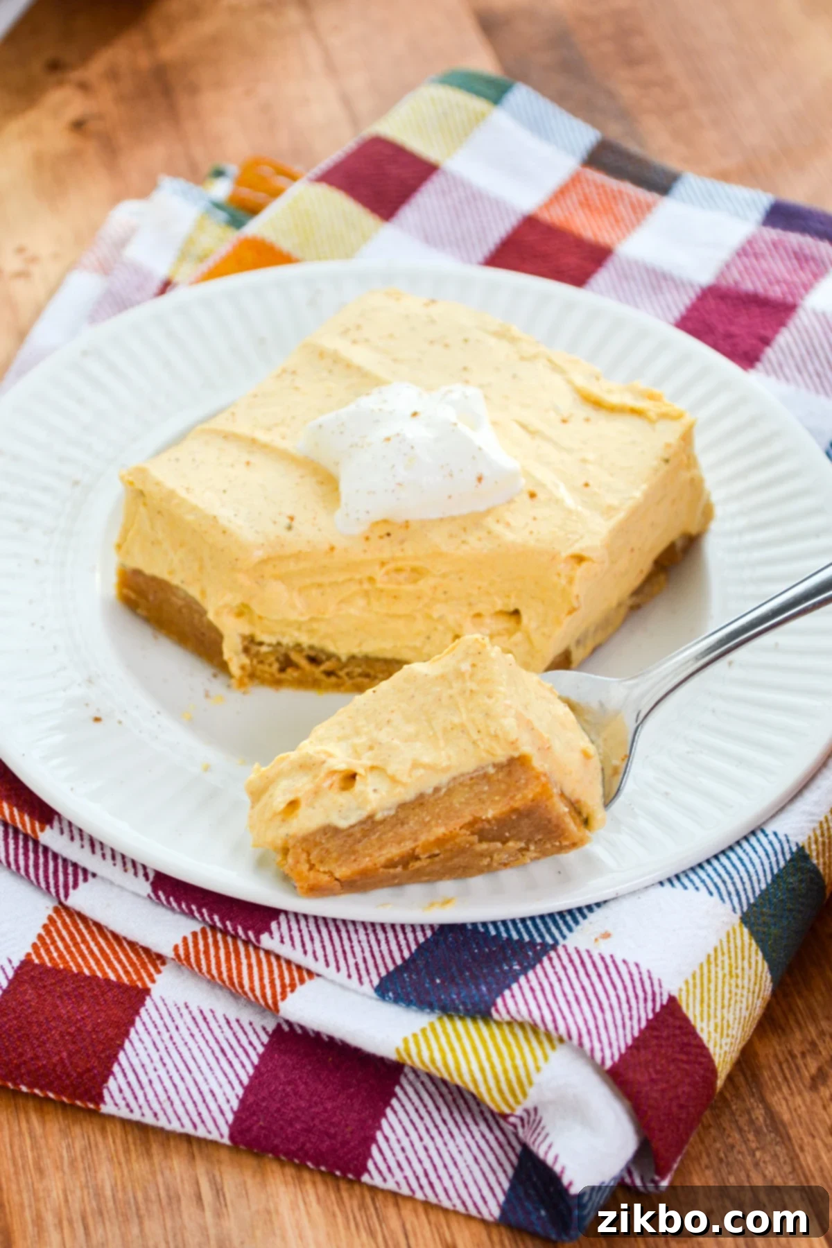 A fork taking a portion of some pumpkin cheesecake bars, highlighting the creamy texture.