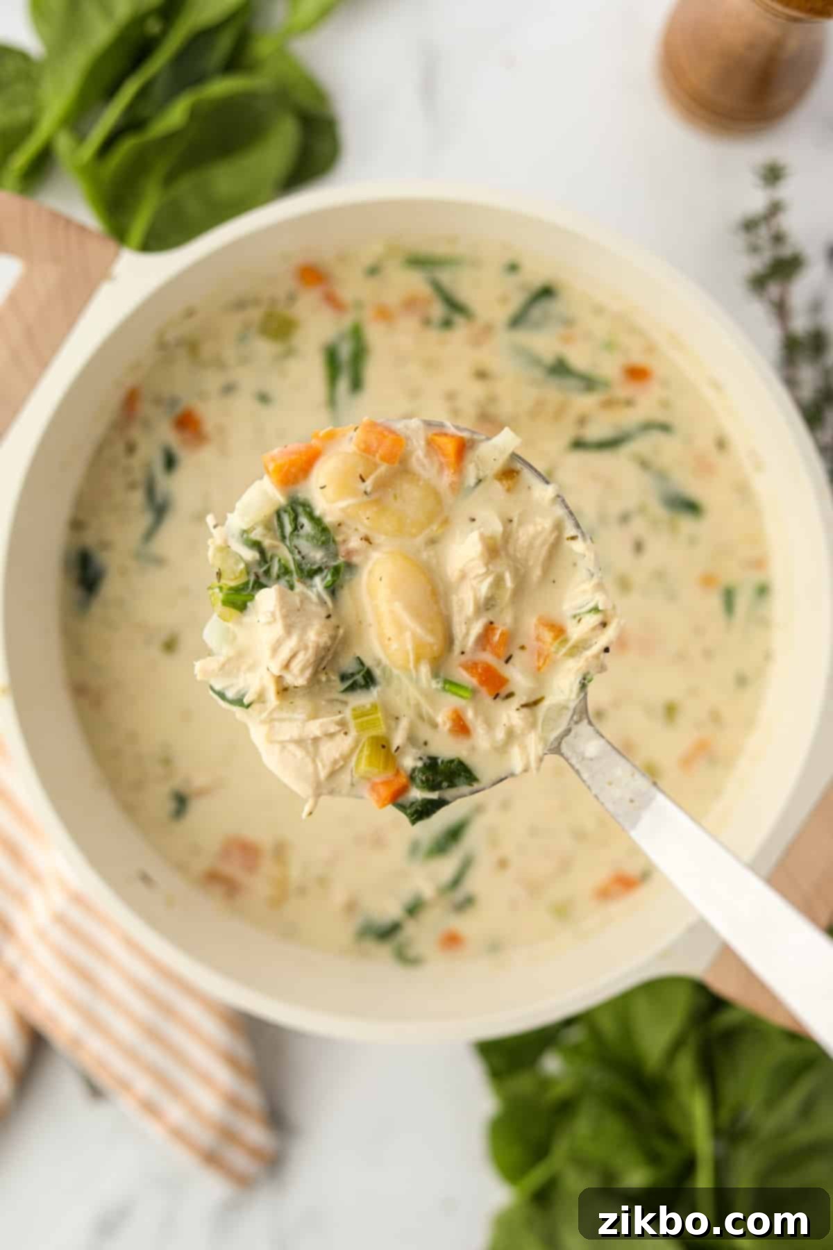 A ladle lifting creamy turkey gnocchi soup from a pot, showcasing its rich texture and ingredients.