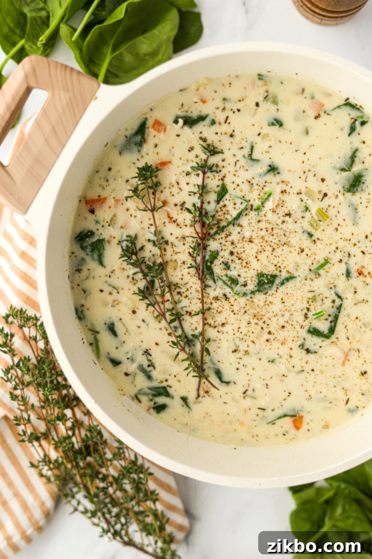 A pot of rich, creamy soup garnished with fresh thyme sprigs, ready to be served.