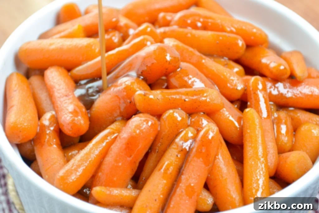 A thickened glaze being poured on top of a bowl of baby carrots.