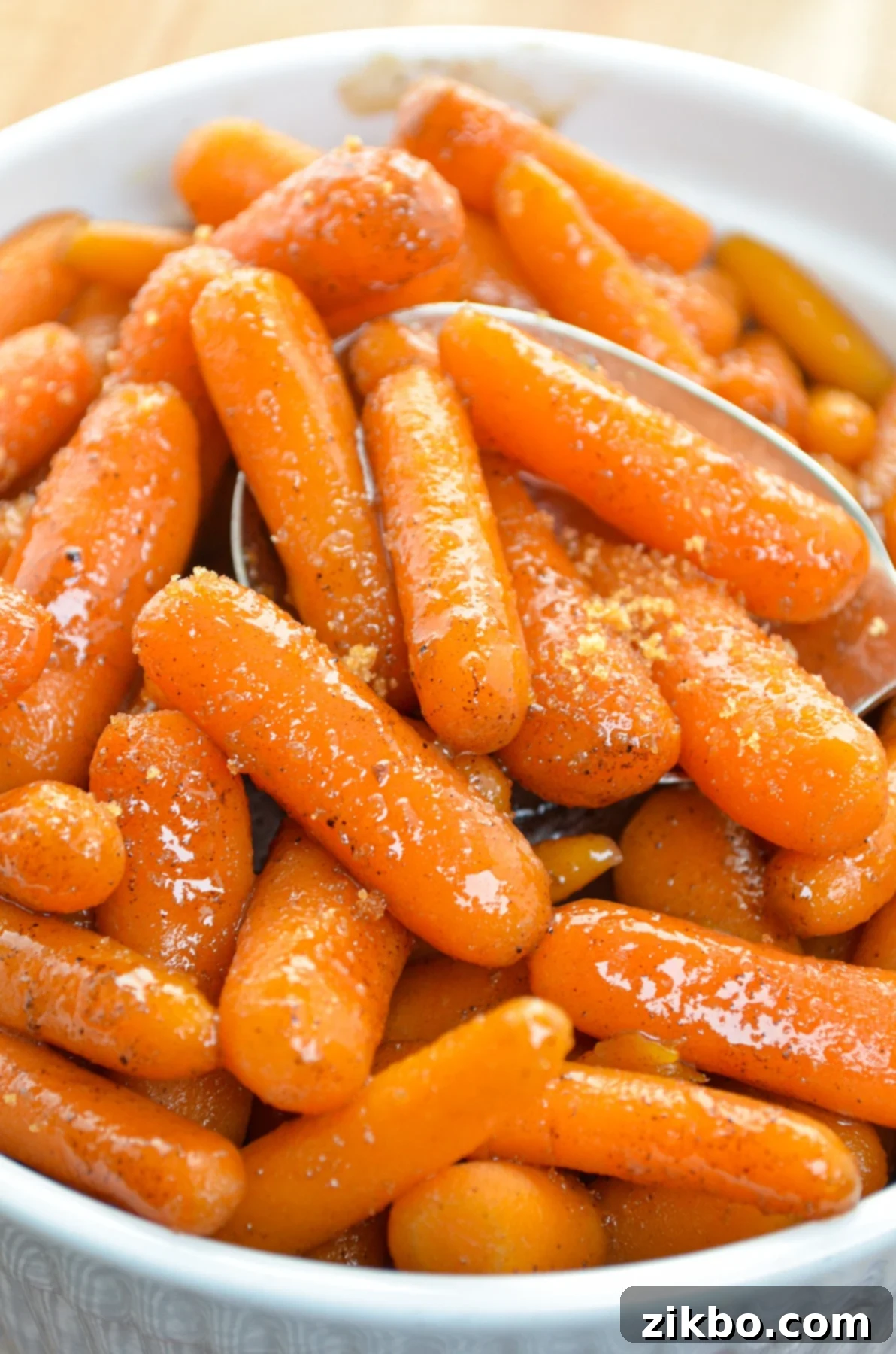 A white serving dish with maple glazed carrots in it. Sprinkled with brown sugar.