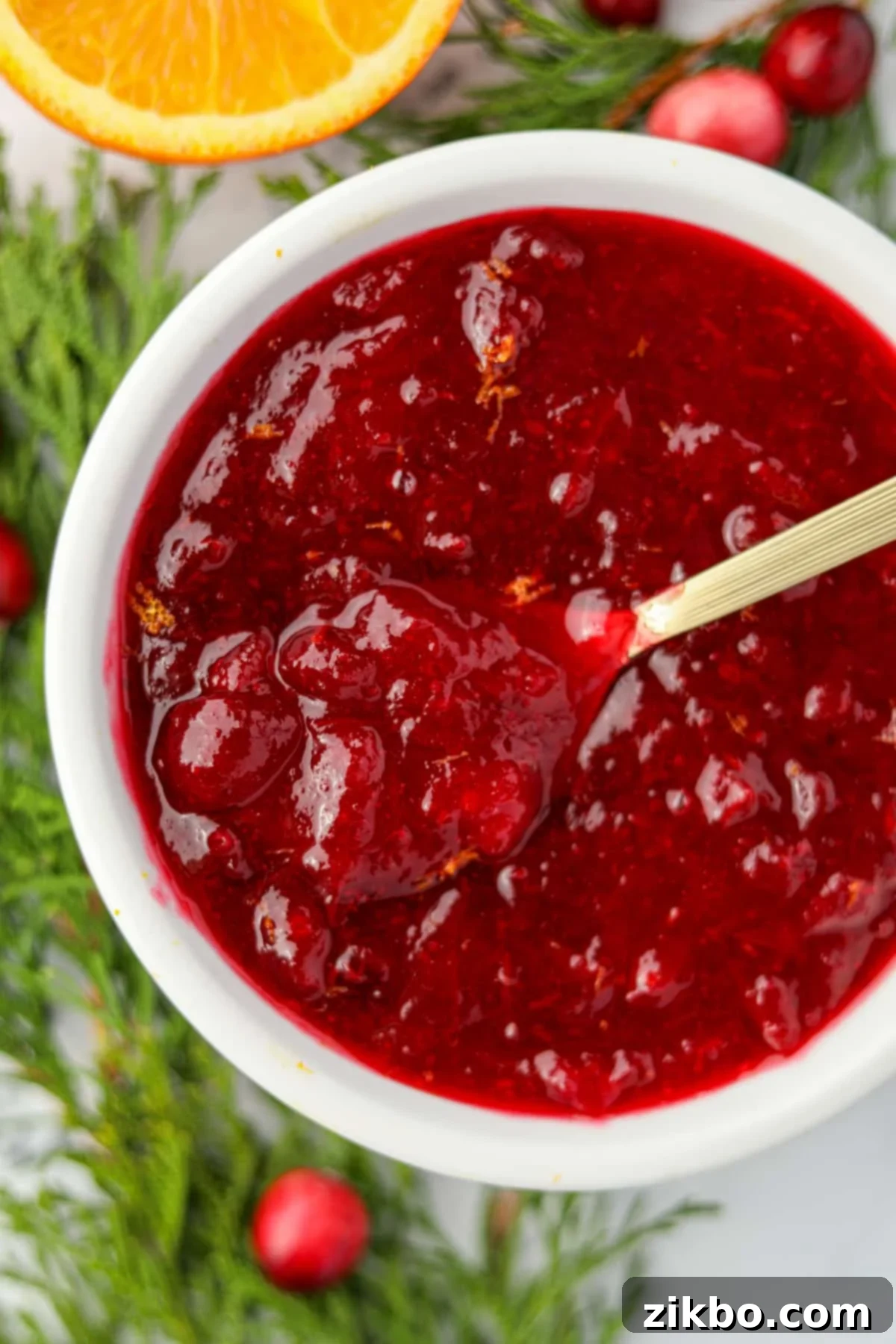 Cranberry Sauce From Scratch 5 A small bowl filled with cranberry sauce, and a gold spoon stirs the contents.