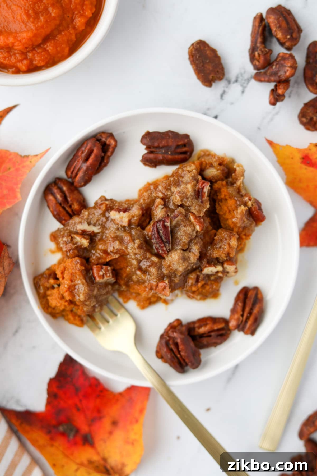 A plate with a generous scoop of pumpkin casserole topped with crunchy pecans, ready to be enjoyed.