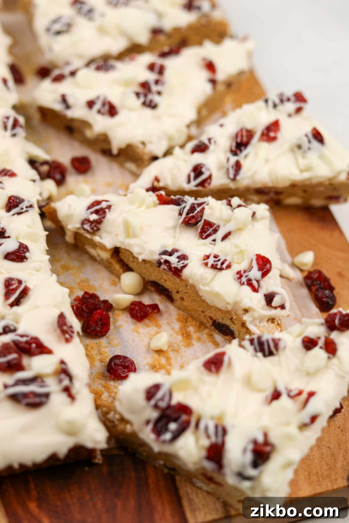 Heavenly Cranberry Bars 2 Triangle cookie bars topped with cream cheese frosting and dried cranberries.