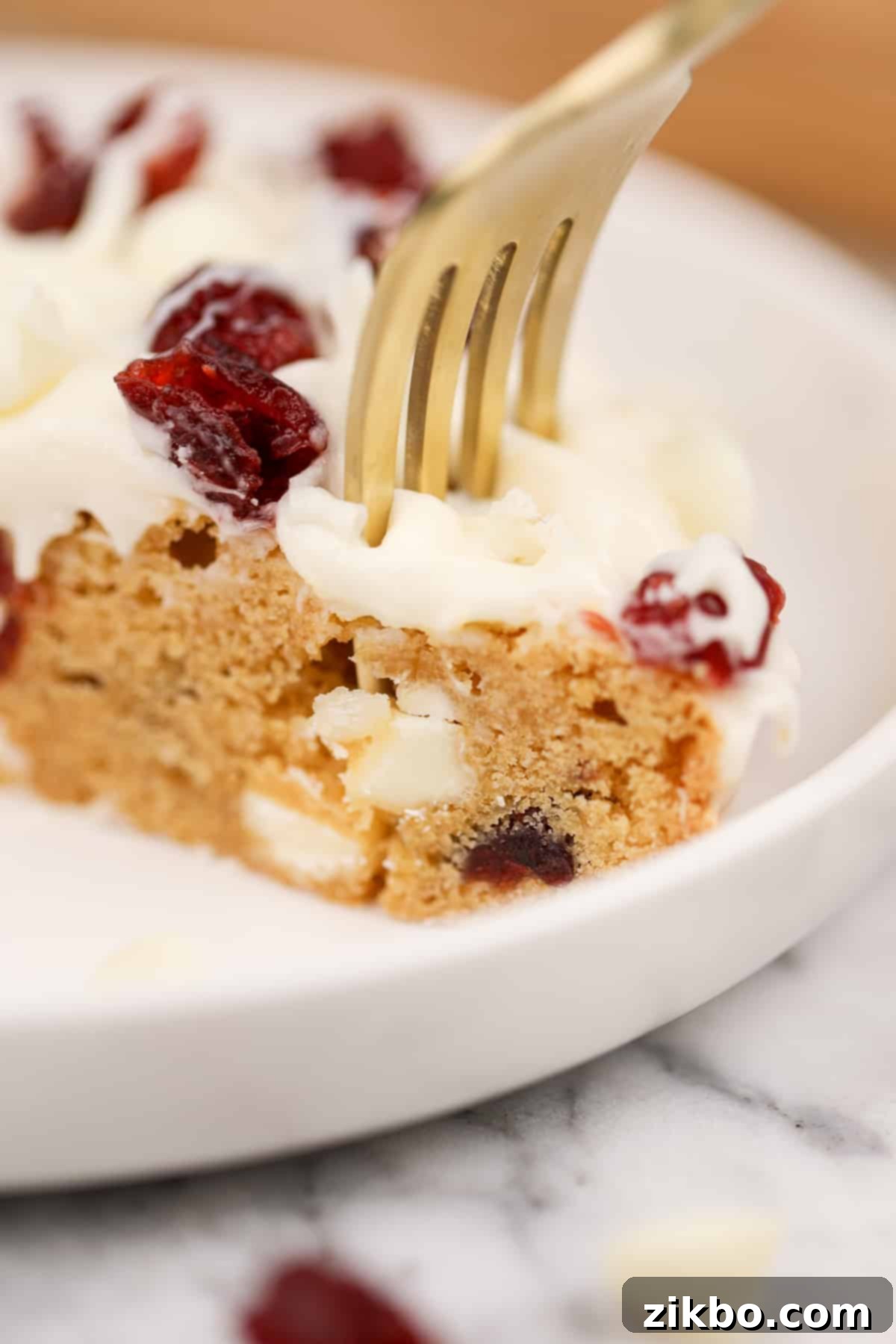 Heavenly Cranberry Bars 11 A fork sinking into a soft blondie layer that's topped with cream cheese frosting.
