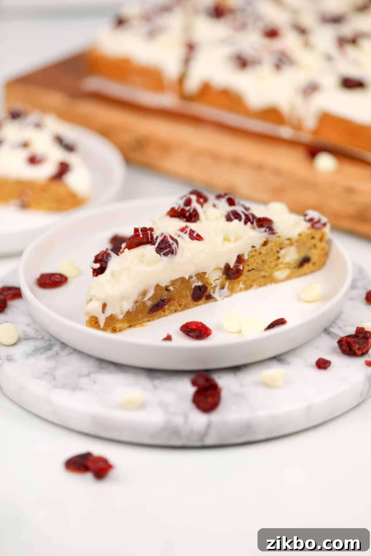 Heavenly Cranberry Bars 10 A triangular blondie bar topped with cream cheese frosting and dried cranberries.