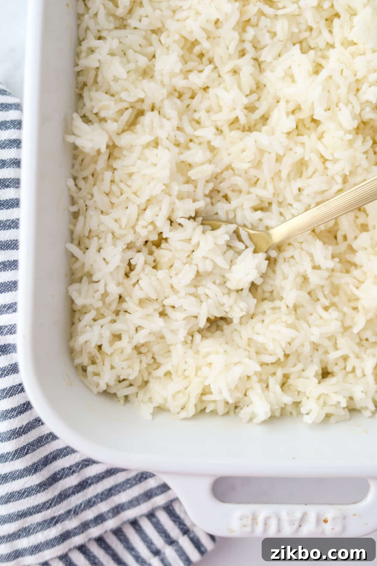Golden Baked Rice 2 A spoon scooping perfectly cooked, fluffy white rice from a baking dish, ready to be served.