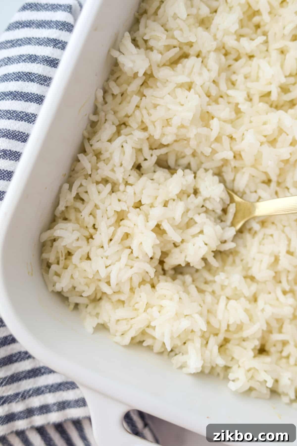 Golden Baked Rice 6 A baking dish filled with perfectly fluffy baked rice, with a serving spoon taking a generous portion, emphasizing the ease of serving.