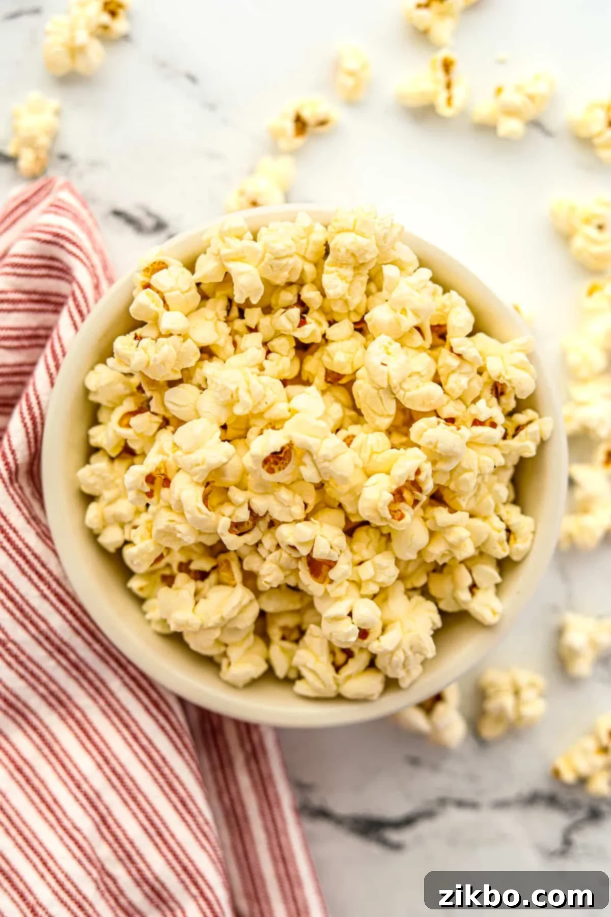 A bowl of buttery popcorn with a red and white napkin on the side, ready for movie night.