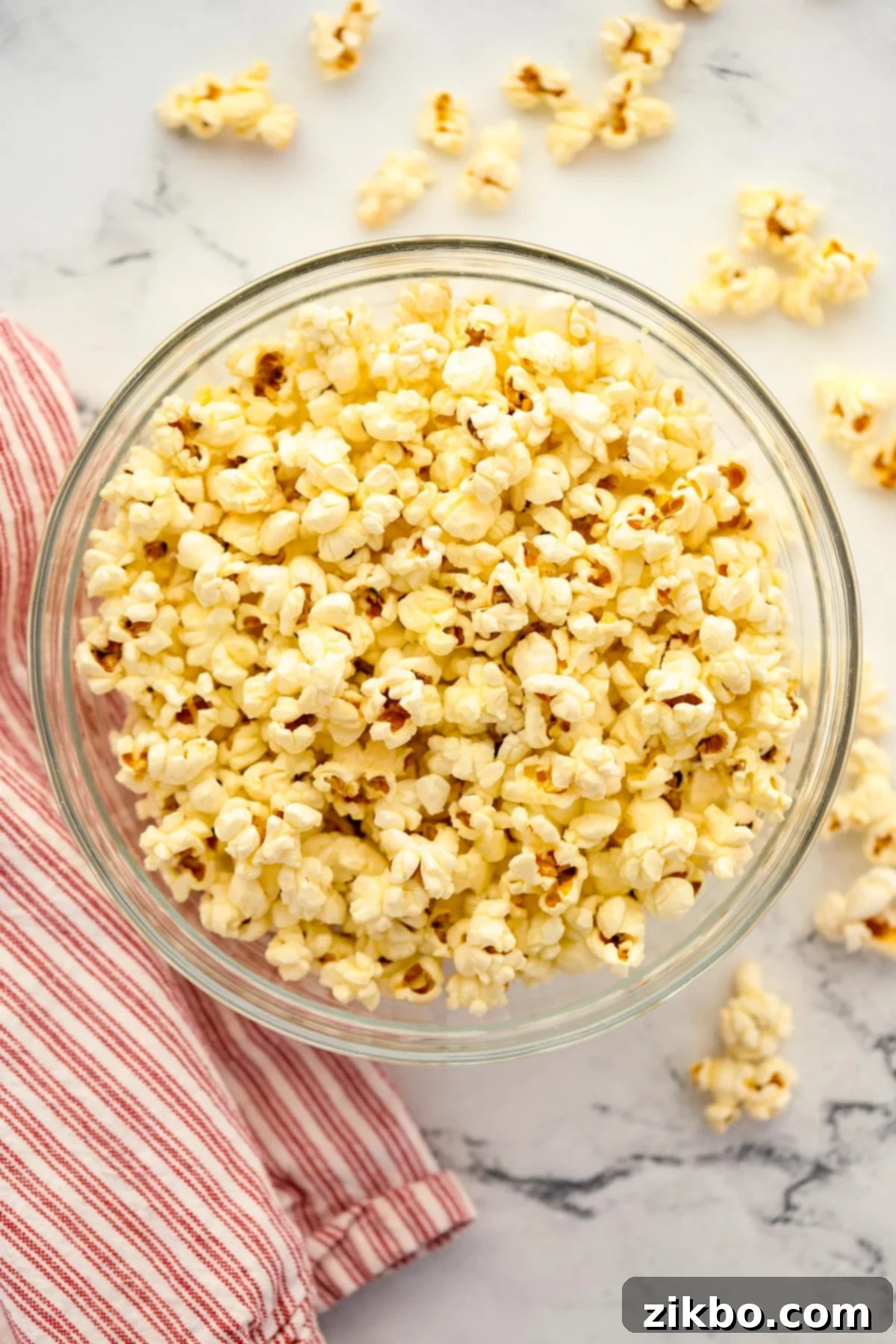 A large bowl of fluffy popcorn with a white and red napkin on the side, ready for serving at a movie night.