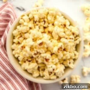 A bowl of perfectly buttery popcorn on a marble background, ready to be enjoyed as a snack.