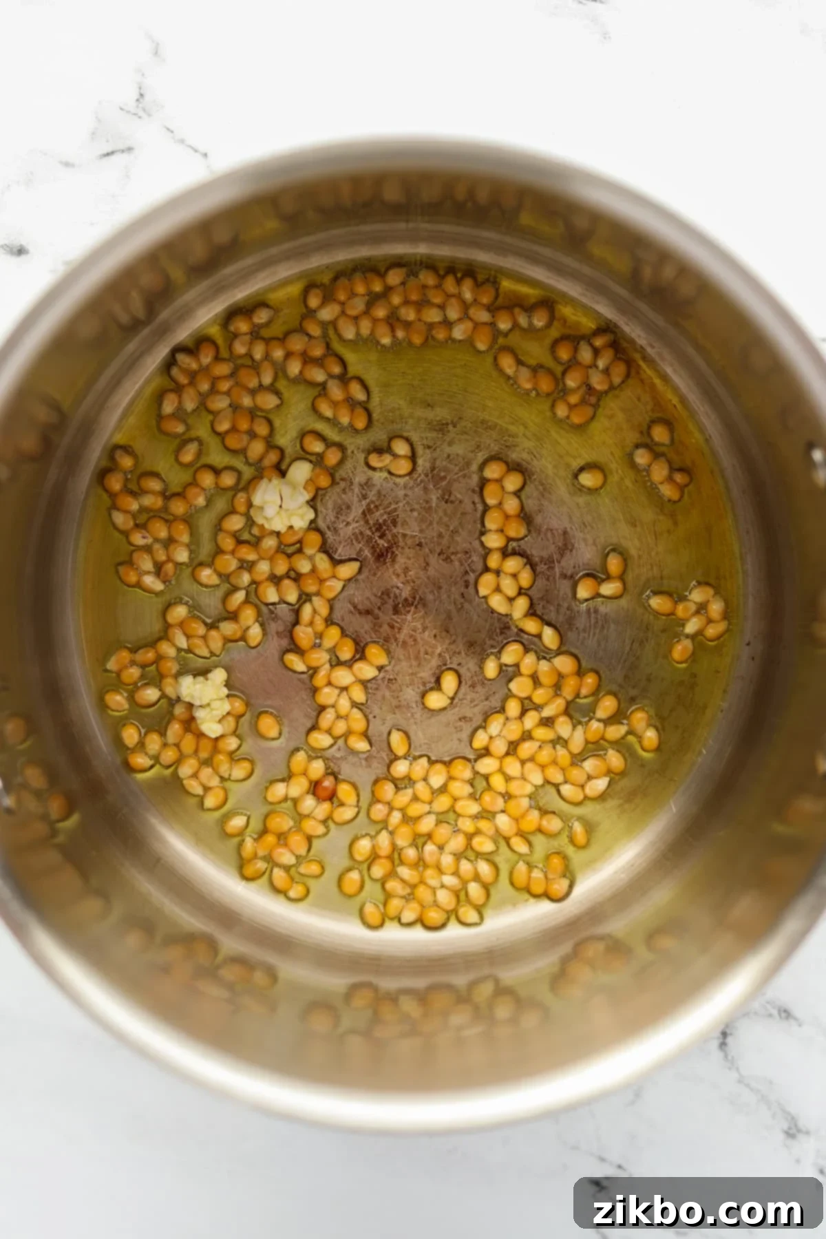 A large pot filled with oil and a few popcorn kernels, illustrating the test kernel method for stovetop popcorn.