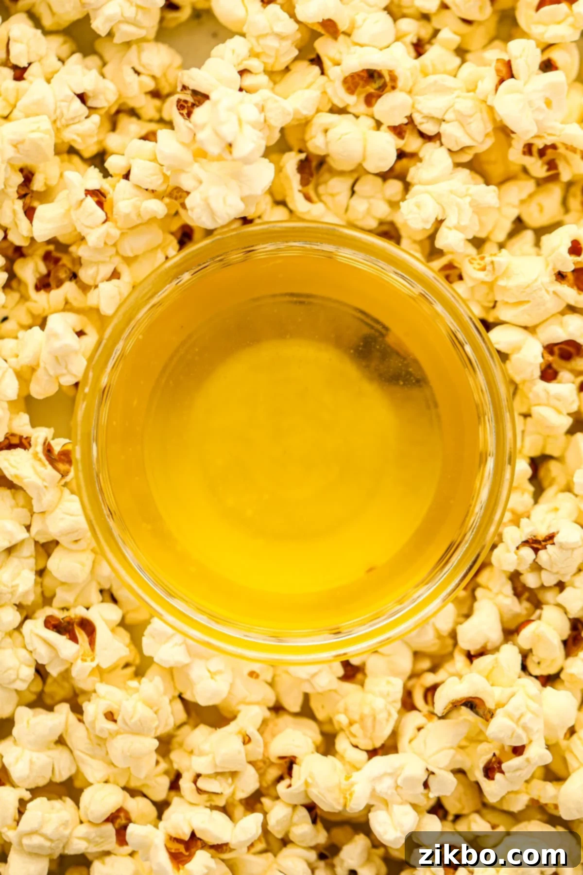 Clarified butter in a small dish surrounded by popcorn, showcasing its rich, golden appearance.