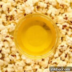 A small bowl of clarified butter with popcorn all around the bowl.