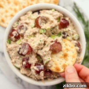 Dipping a cracker into a bowl of tuna salad with grapes.