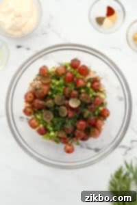 A bowl with grapes, fresh herbs, and tuna ready to be mixed.