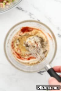 Whisking together a dressing in a small bowl.