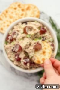 Dipping a water cracker into a bowl of tuna salad.