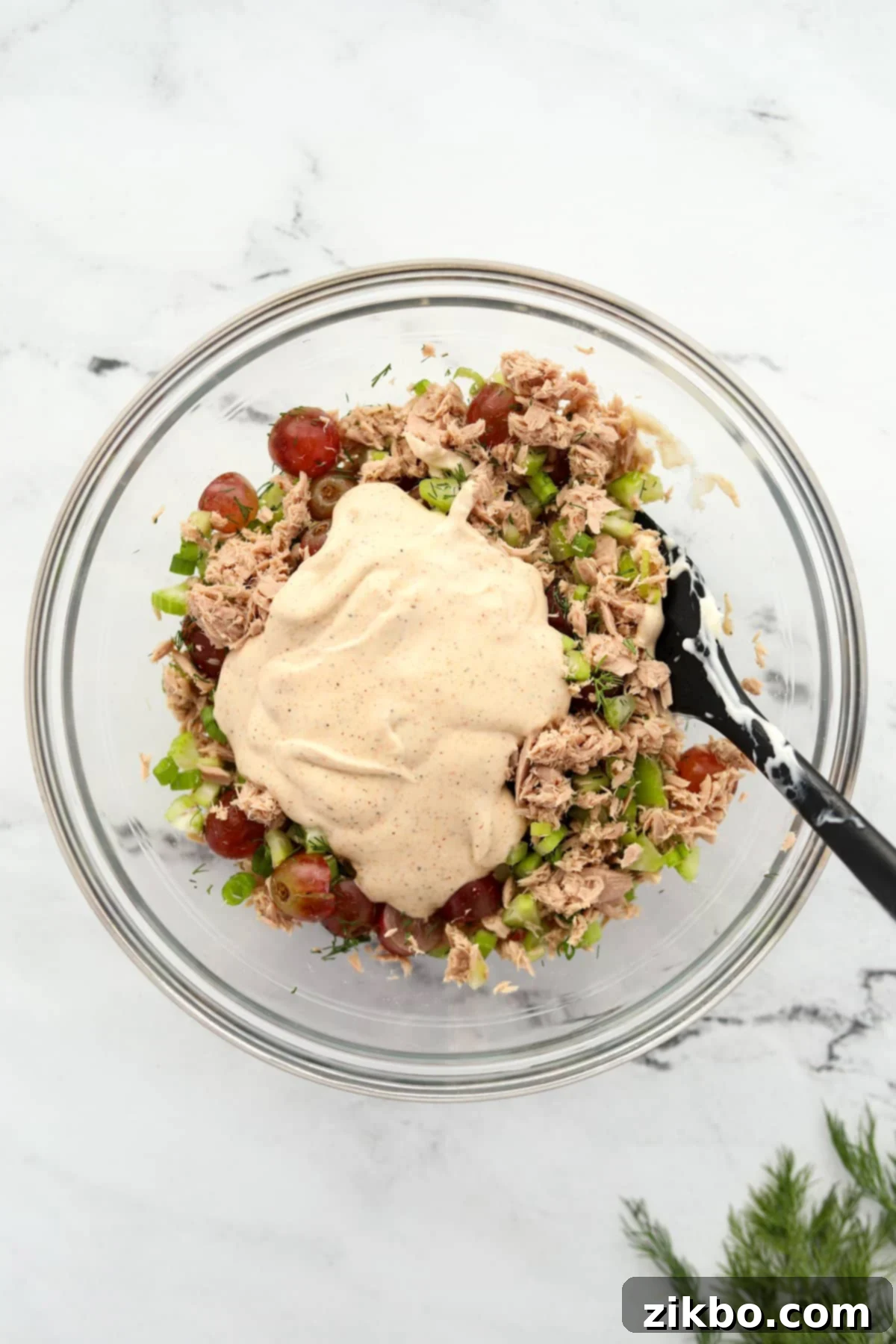 Mixing together the tuna salad ingredients with the creamy dressing in a large bowl.