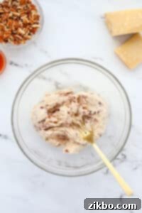 A fork mashing soft cheese in a mixing bowl.