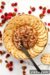 An appetizer knife taking a portion of a pecan-coated cheese ball.