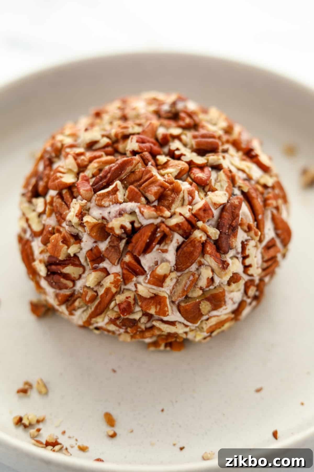A beautifully prepared Boursin cheese ball, completely coated in chopped pecans, displayed on a serving platter.