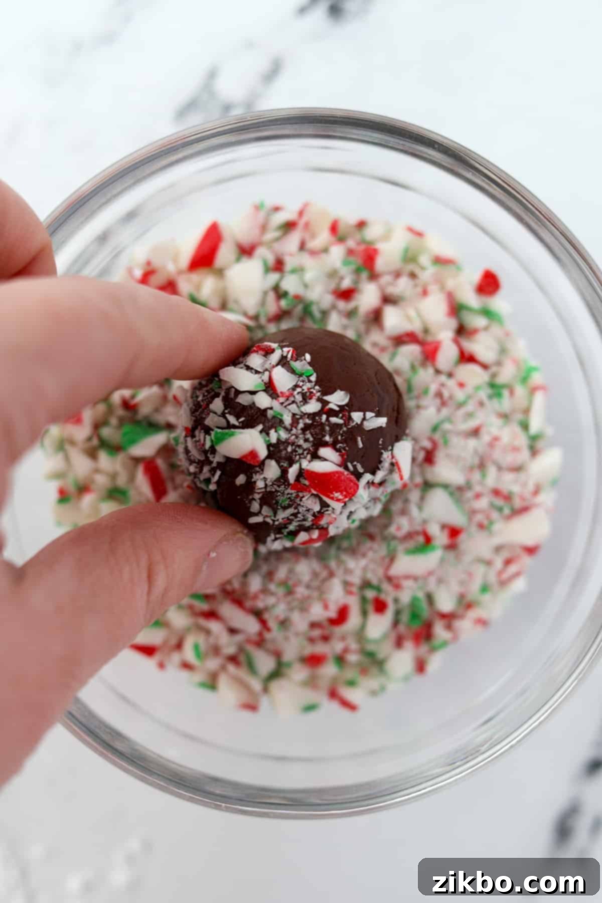 Rolling a chocolate ball in crushed candy cane dust.