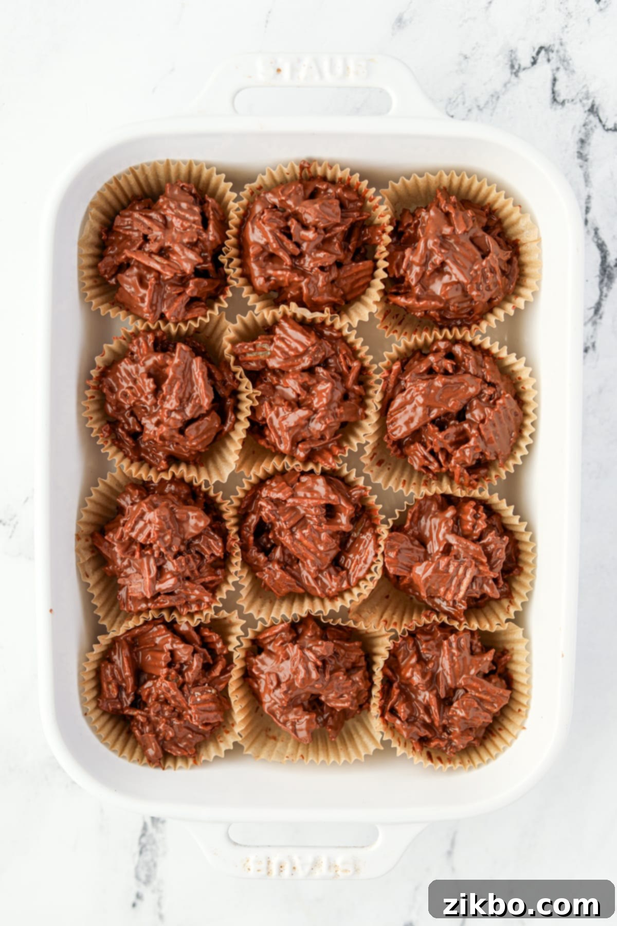 A baking dish filled with chocolate potato chip clusters in muffin liners, ready for setting.
