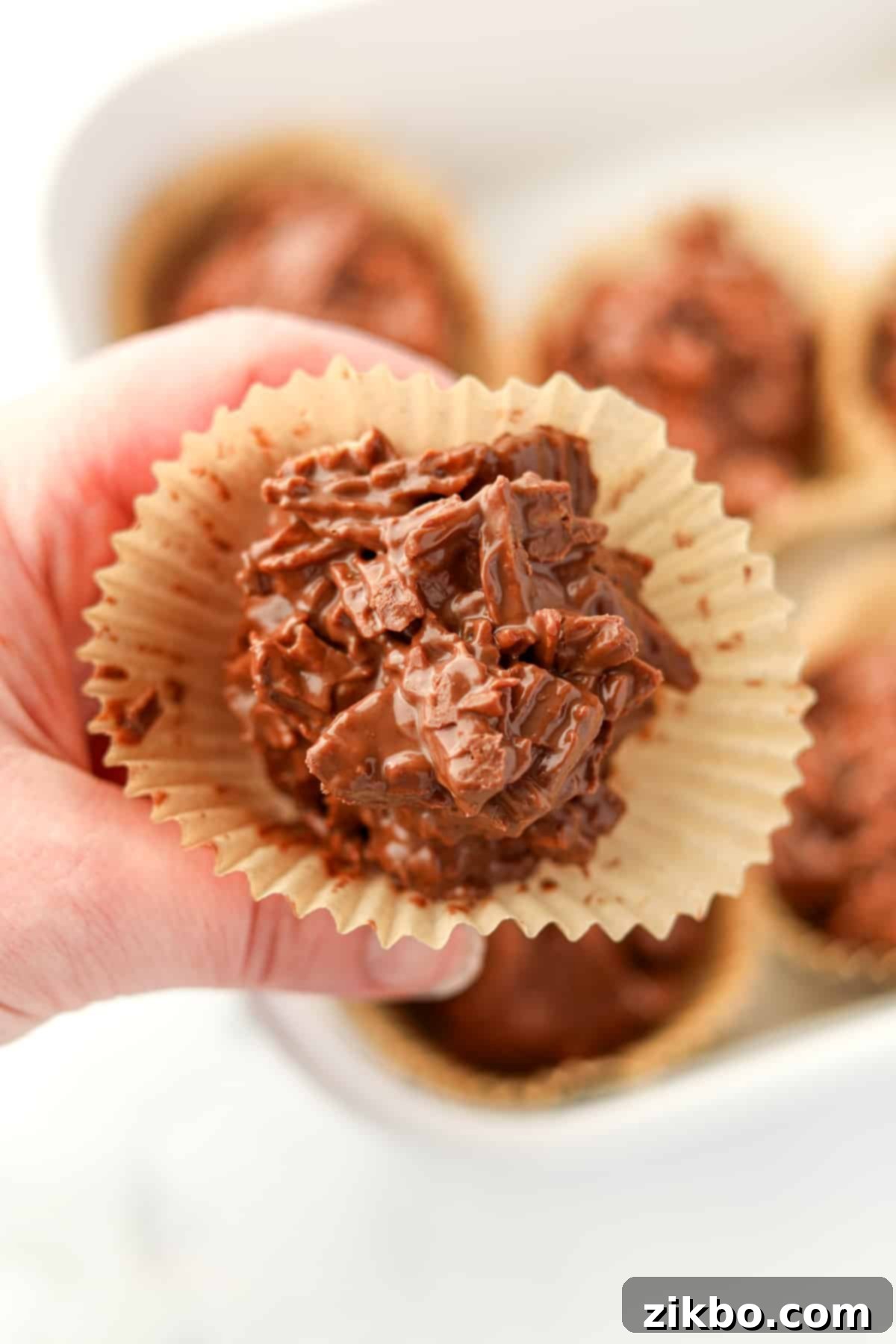 A close up of a perfectly set chocolate potato chip cluster, still in its muffin liner, ready to be enjoyed or gifted.