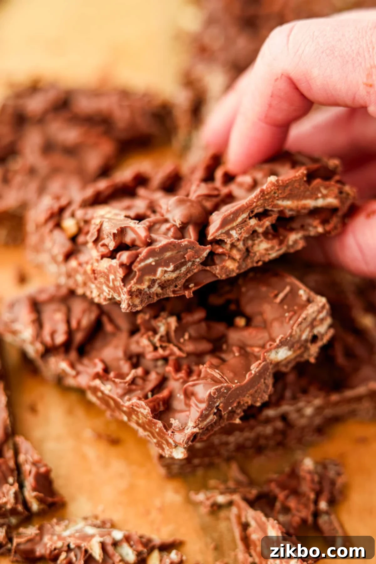 A hand picking up a piece of chocolate bark made with wavy chips, highlighting the texture.