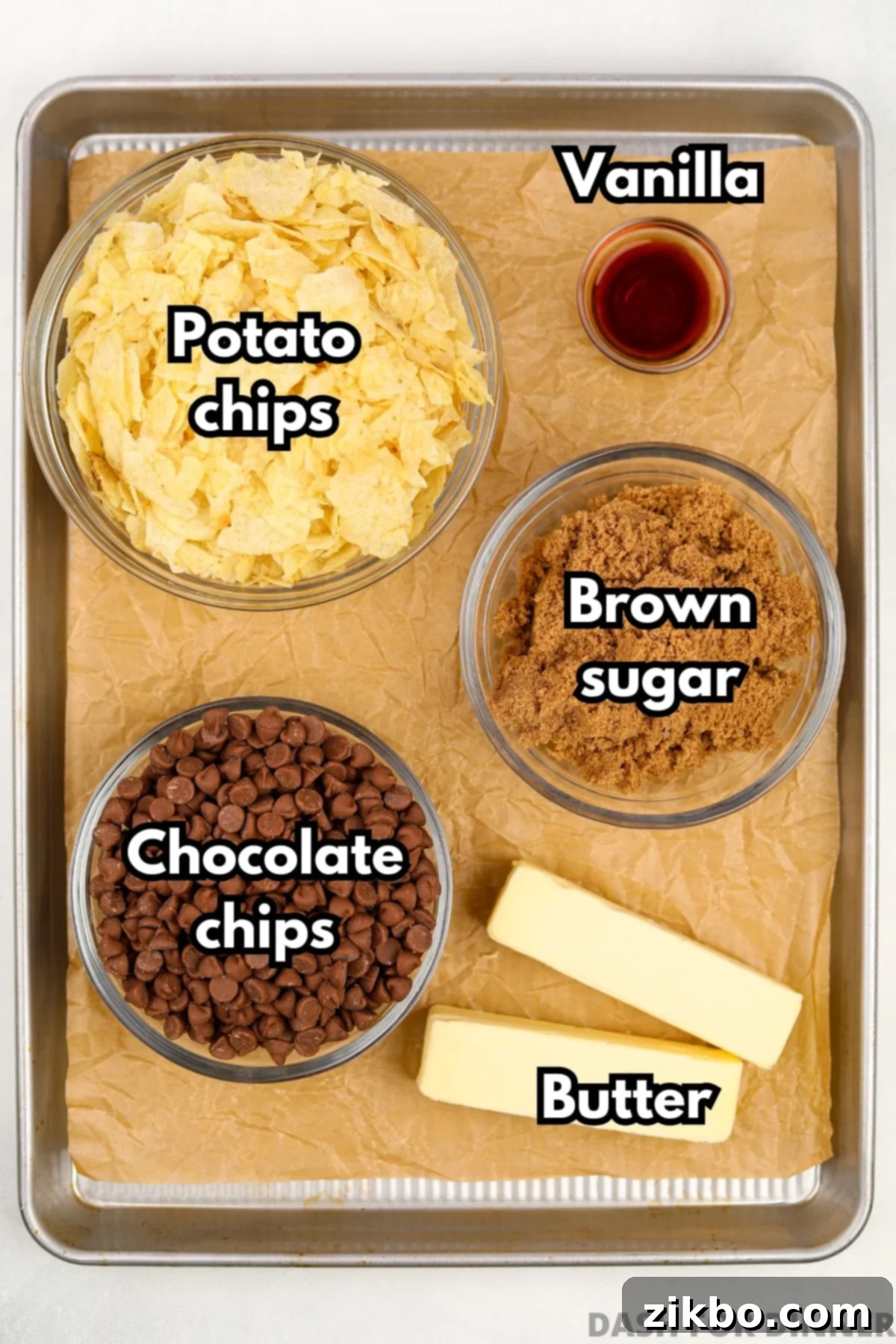The five key ingredients for making potato chip toffee: a bag of potato chips, sticks of butter, brown sugar, a bottle of vanilla extract, and chocolate chips.