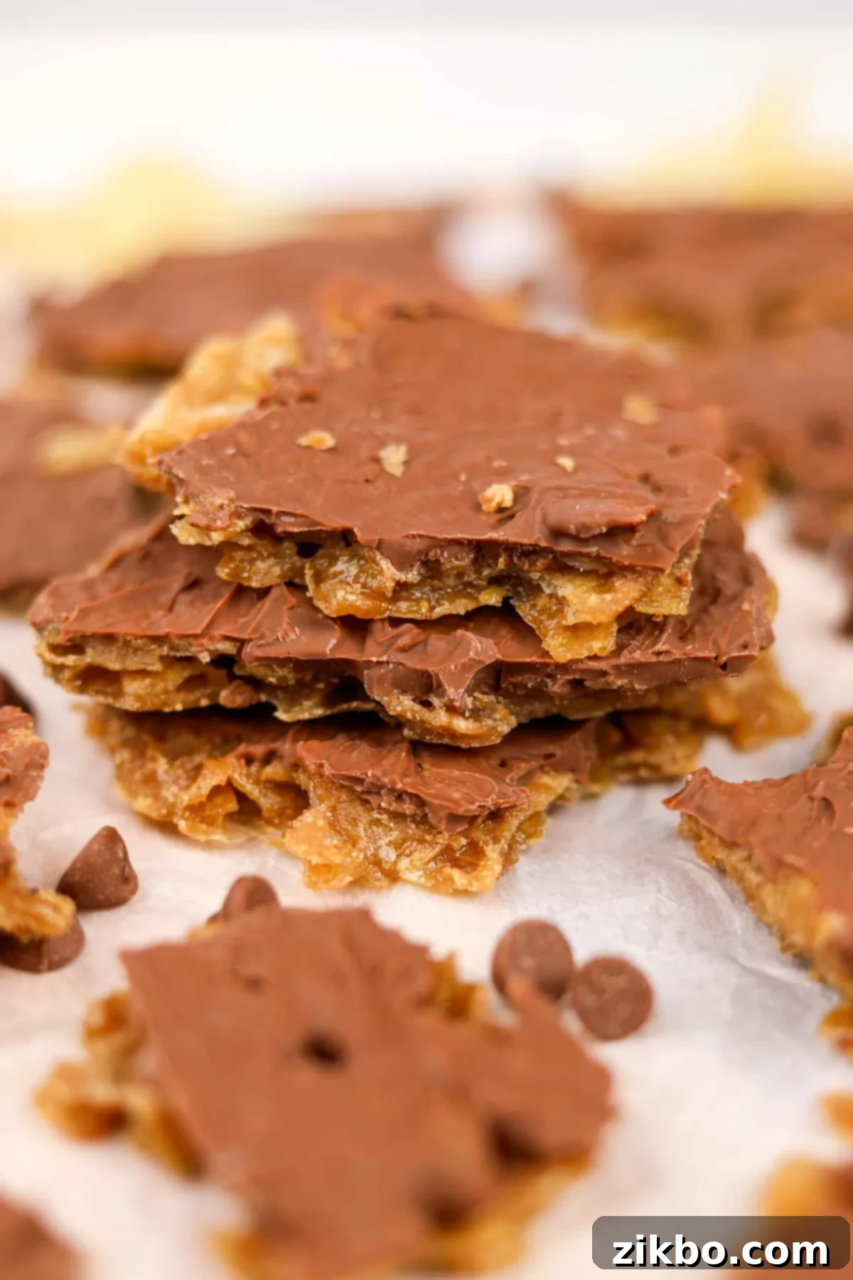 A beautiful stack of homemade potato chip toffee pieces on a parchment paper-lined cutting board, ready for presentation or serving.