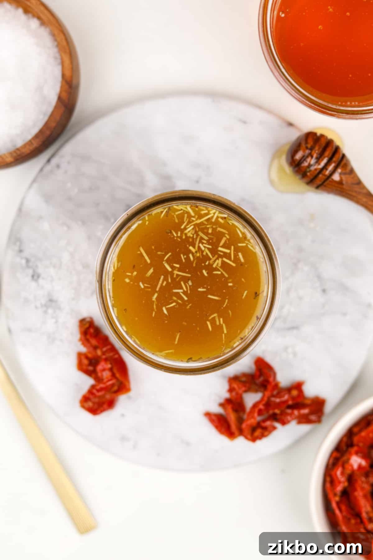 A small jar of homemade vinaigrette with dried spices floating.