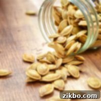 A jar of pumpkin seeds, spilled over onto a wood table.