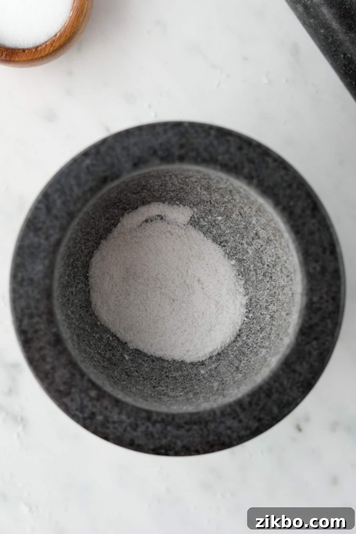 The bowl of a mortar filled with powdery ground salt.