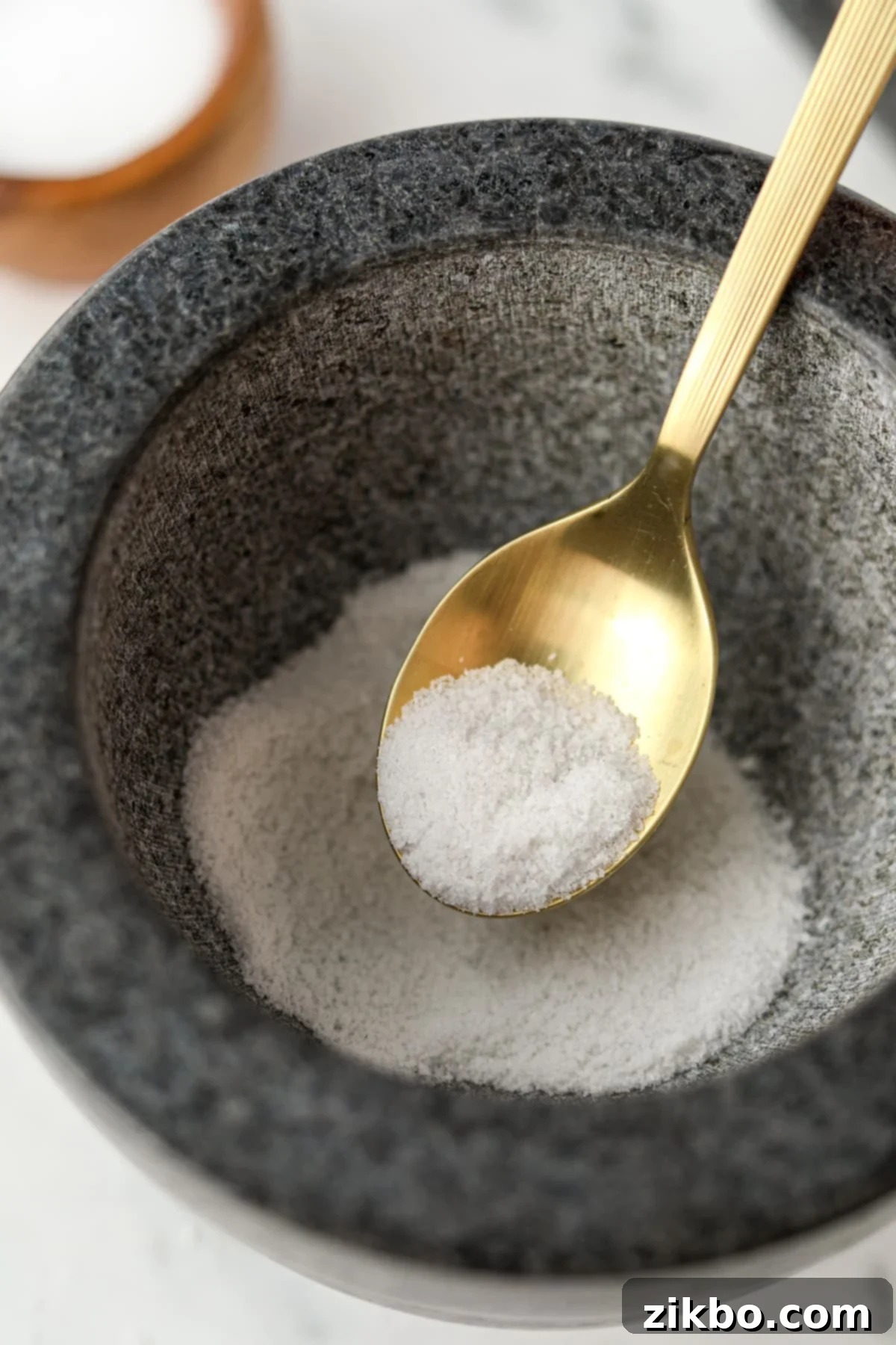 A golden spoon filled with ground salt.