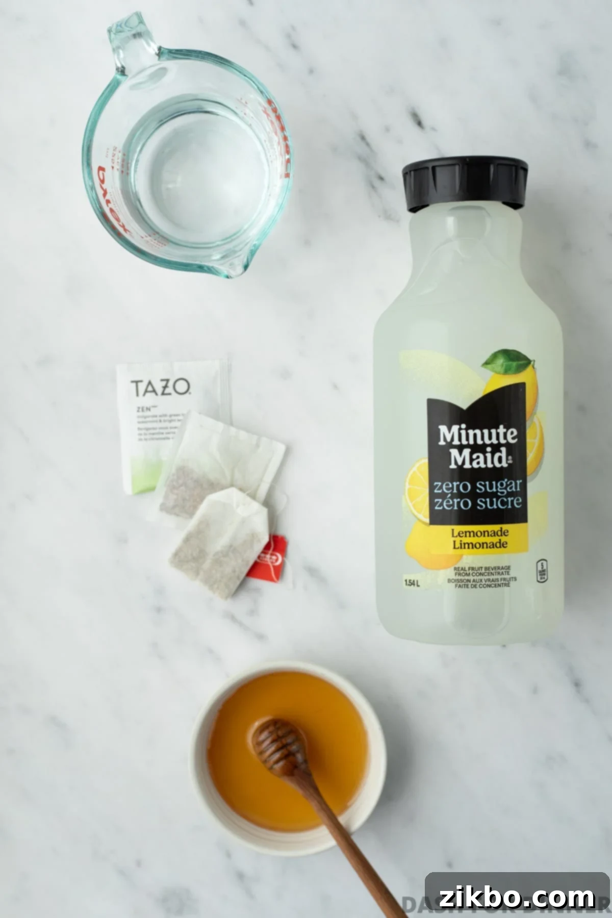 The ingredients needed to make homemade Medicine Ball tea, including lemonade, honey, various tea bags, and fresh water.