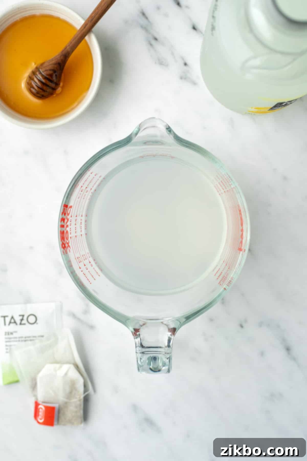 A measuring cup filled with a warm mixture of lemonade and water.